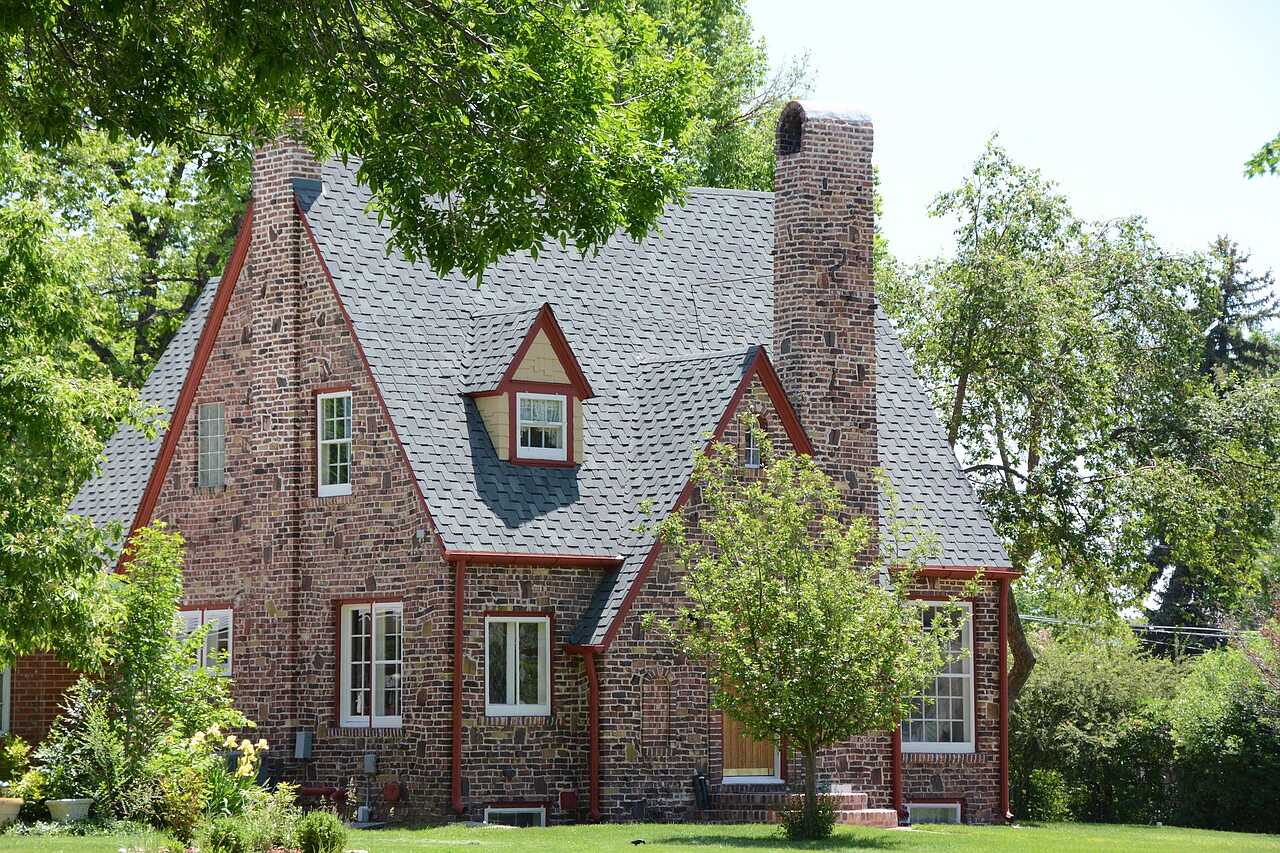 A 1920s brick Tudor cottage with a steep roof and arched entry