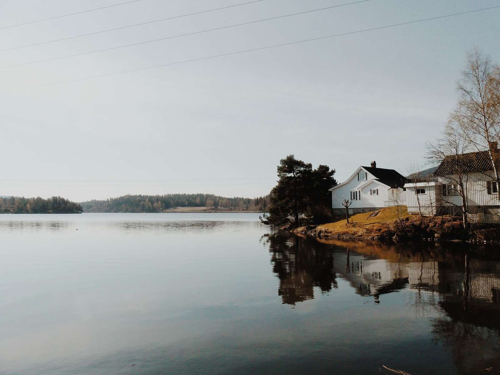 White cottages on a lakeshore reflected in calm water