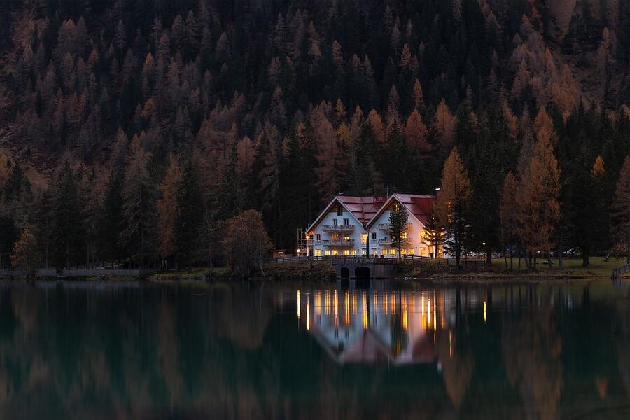 A house among autumn trees reflected in still water at twilight