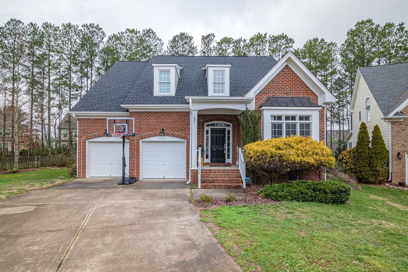 A brick two-story house with a two-car garage and a basketball hoop