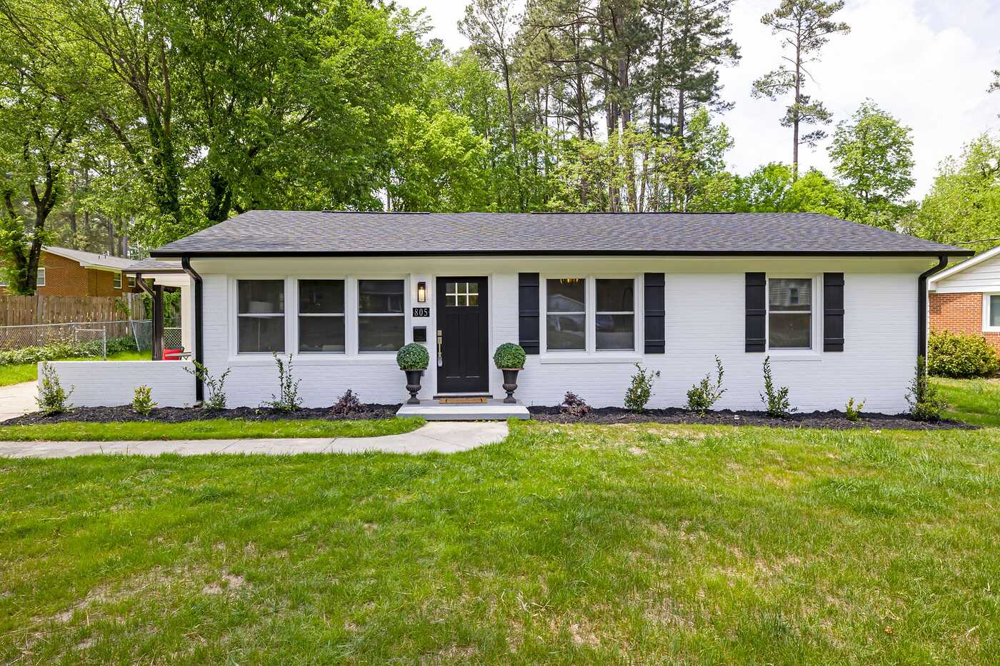 A small white single-story house with a front lawn