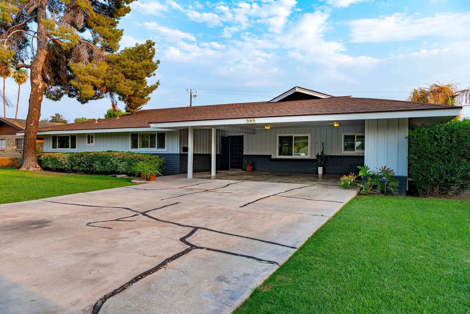 A mid-century single-story house with a low roof and a wide driveway